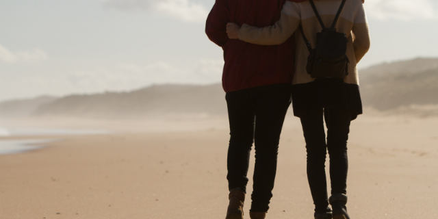 Casal abraçados e caminhando na praia