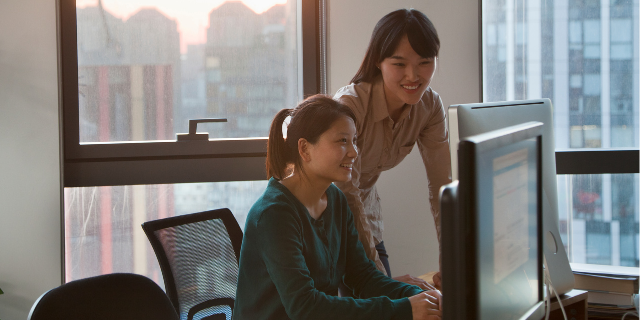 Duas mulheres sorrindo trabalhando juntas em um escritório