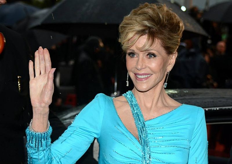 Jane Fonda acenando e sorrindo usando vestido