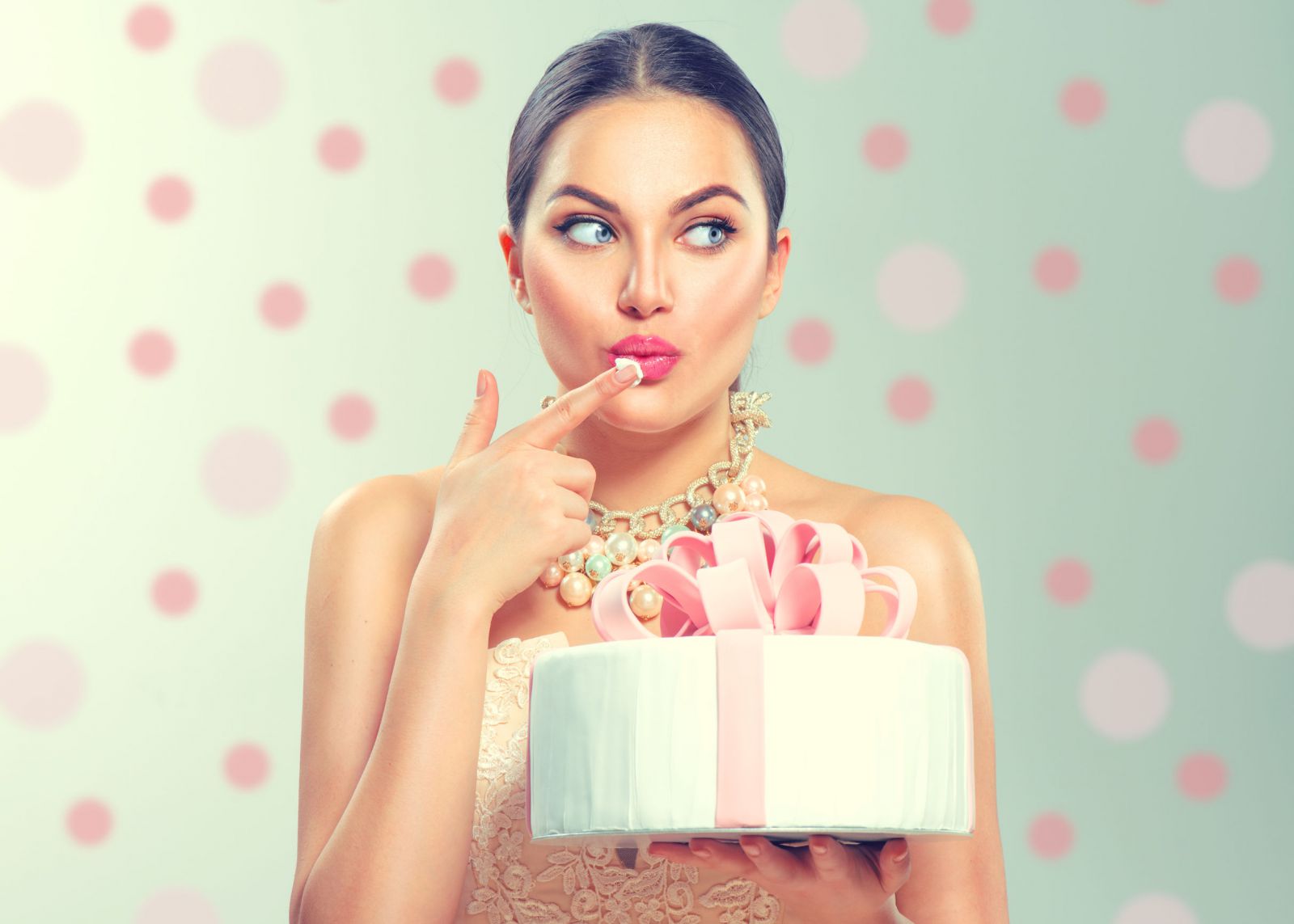 Mulher comendo um pedaço de seu bolo de aniversário com os dedos.