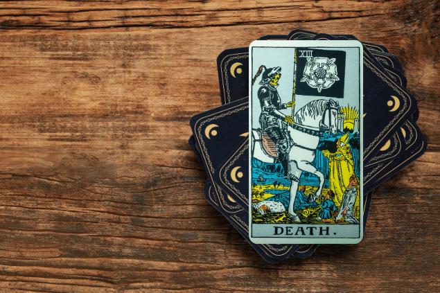 Carta A Morte sobre deck de tarot, em fundo de madeira.