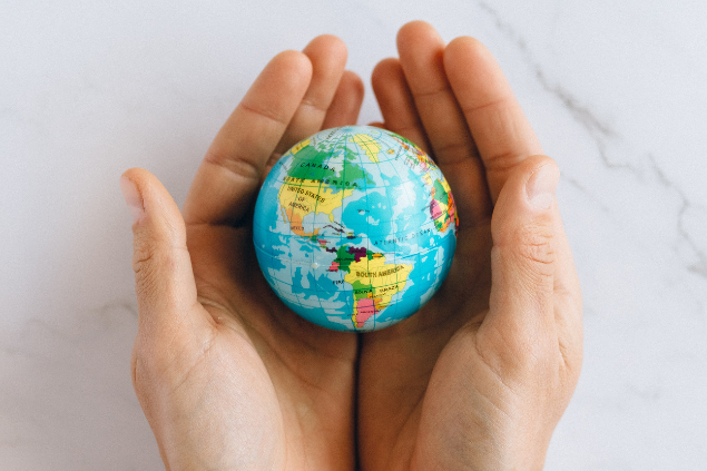 Uma mão segurando um planeta Terra de plástico