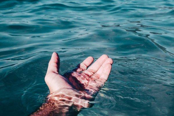 Pessoa com a mão imersa na água do mar