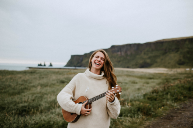 Mulher sorrindo enquanto toca um ukulele