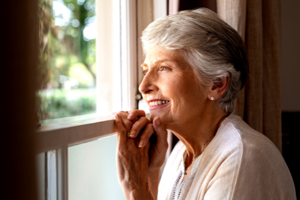 Uma senhora feliz olhando pela janela