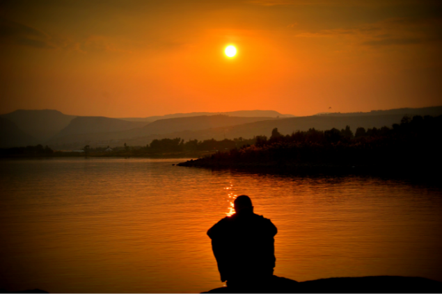 Homem sentado triste assistindo ao pôr do sol
