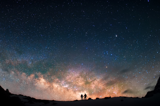 Duas pessoas olhando para um céu estrelado