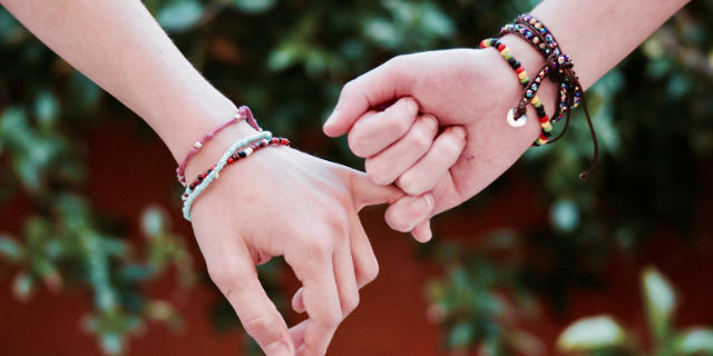 Duas mãos com os dedos mindinhos entrelaçados