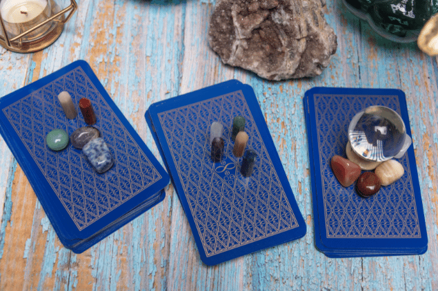 Imágenes de Juan Ruiz / Canva Algumas cartas de Tarot viradas para baixo estão em destaque na imagem. Ao lado, há uma vela e outros objetos.