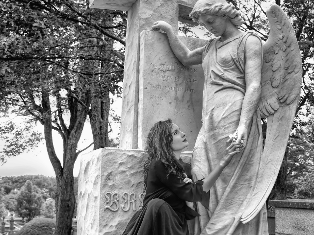 Mulher ao lado de estátua de anjo