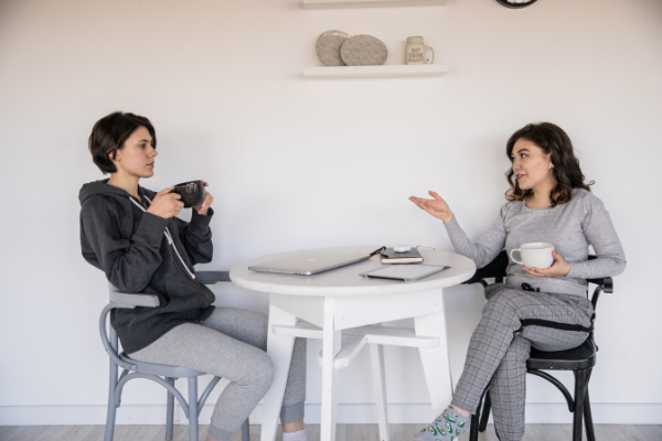 Duas mulheres sentadas na mesa da cozinha conversando