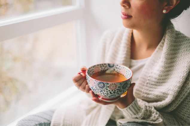 Imagem de uma mulher tomando chá em uma caneca bem grande