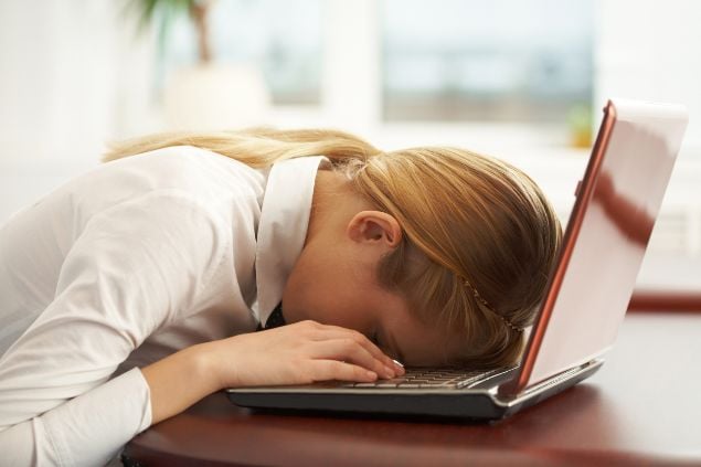 Imagem de uma mulher com o rosto em cima do notebook como se estivesse exausta