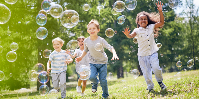 Crianças brincando em meio a bolhas de sabão.