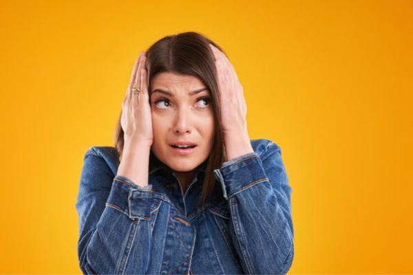 Mulher com as mãos na cabeça e expressão ansiosa
