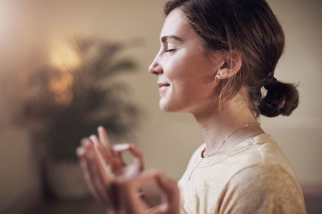 Imagem de uma mulher que parece estar meditando com semblante de calma e com os olhos fechados