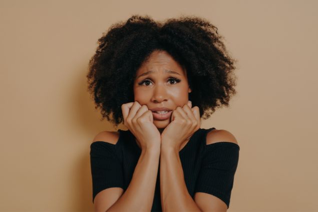 Imagem de uma mulher com expressão de medo e insegurança em um fundo bege