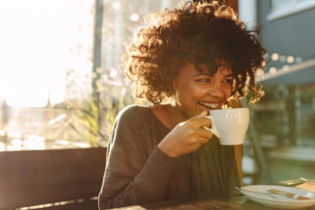 mulher sorridente tomando uma xícara de café
