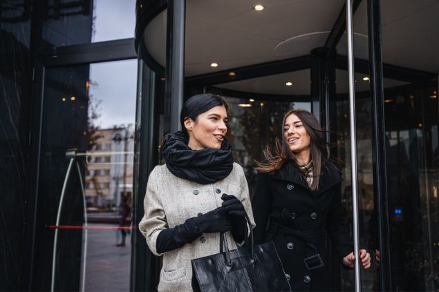 Casal de mulheres elegantes saindo de um hotel