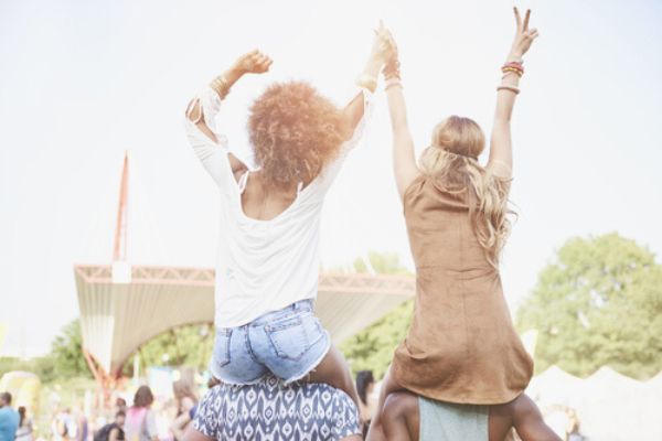 Meninas sentadas no ombro de amigos em um festival
