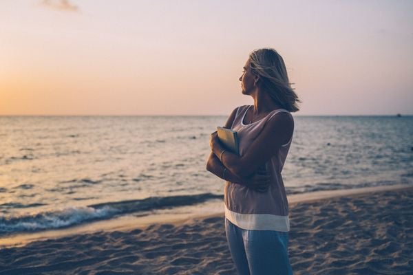 Mulher na beira da praia olhando o horizonte