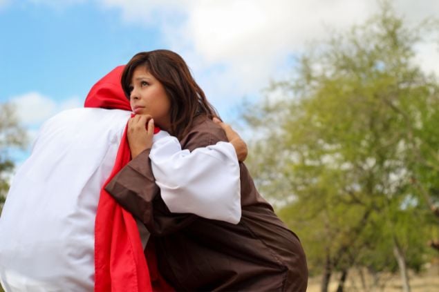 Imagem de uma mulher recebendo um abraço de Jesus que está de costas.
