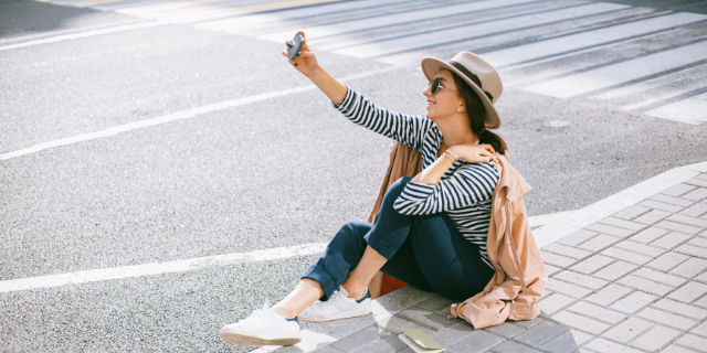 Mulher sentada na rua tirando uma selfie