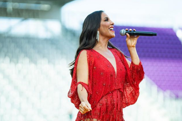 Ivete Sangalo cantando em um palco no estádio de futebol