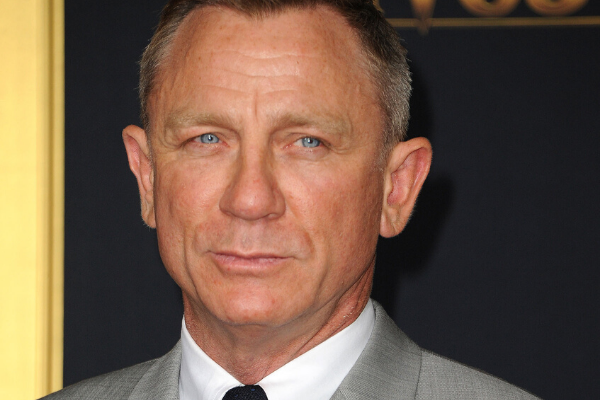 Daniel Craig olhando pra o lado  usando terno e gravata 