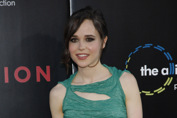 Ellen Page sorrindo e olhando para o lado em uma premiação usando vestido