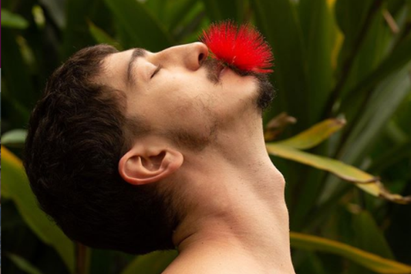 Johnny Massaro de olhos fechados segurando flor com sua boca