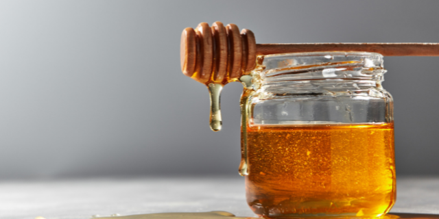 Pote de vidro sobre uma mesa contendo mel