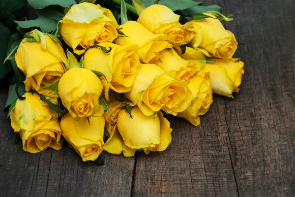 Diversas rosas amarelas em cima de uma mesa de madeira