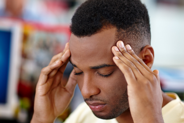 Homem de olhos fechados e mãos nas laterais da cabeça