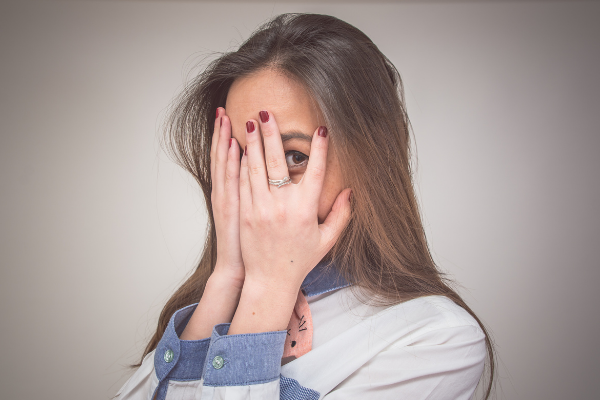 Cristian Negroni / Getty Images / Canva Menina escondendo o rosto com as mãos