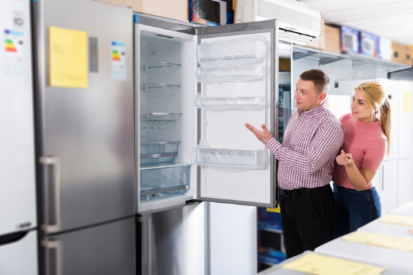 JackF / Getty Images / Canva Casal abrindo uma geladeira nova na loja