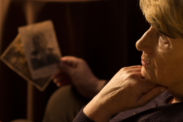 KatarzynaBialasiewicz / Getty Images / Canva Imagem de uma senhora sentada segurando algumas fotos