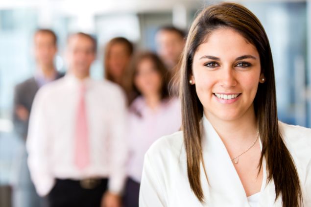 Latino Life / Canva Imagem de uma mulher sorrindo a frente de um grupo
