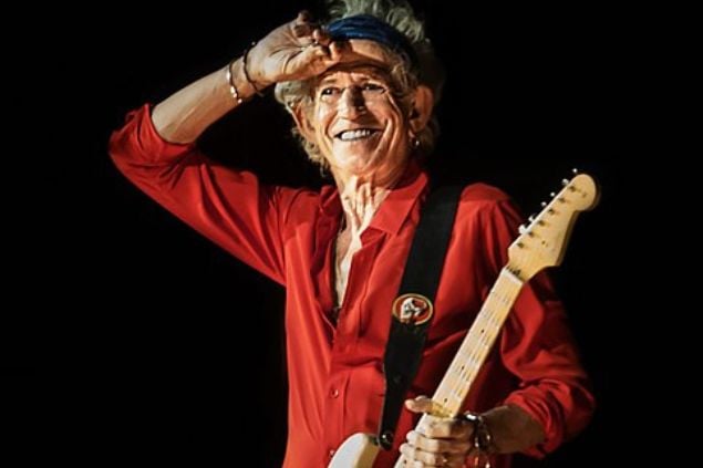 Foto de Keith Richards sorrindo no palco com a guitarra