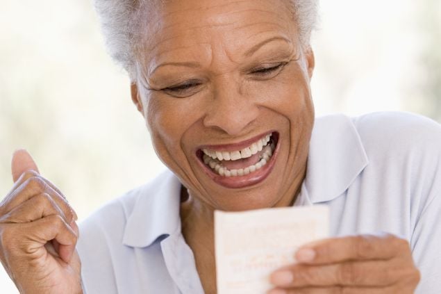 imagem de uma mulher sorrindo olhando para um bilhete de loteria