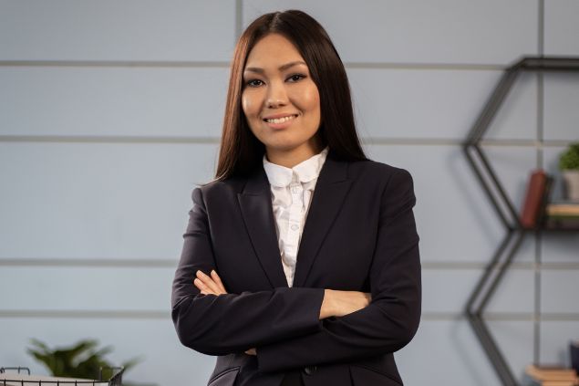 Imagem de uma mulher com roupas sociais de braços cruzados e sorrindo