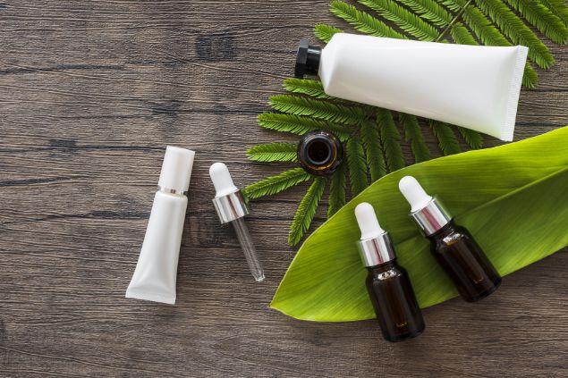 Imagem de produtos cosméticos em cima de uma mesa e dois tipos de plantas 