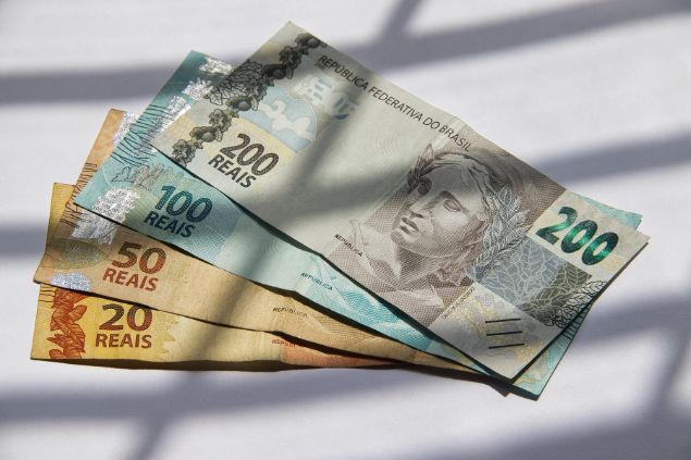 Imagem de notas de 20,50,100 e 200 reais em cima de uma mesa