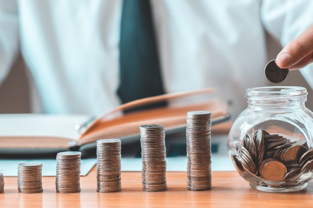 Imagem de uma pessoa juntando moedas dentro de um vidro pequeno