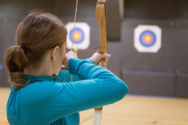 Imagem de uma mulher com um arco e flecha na mão mirando no alvo