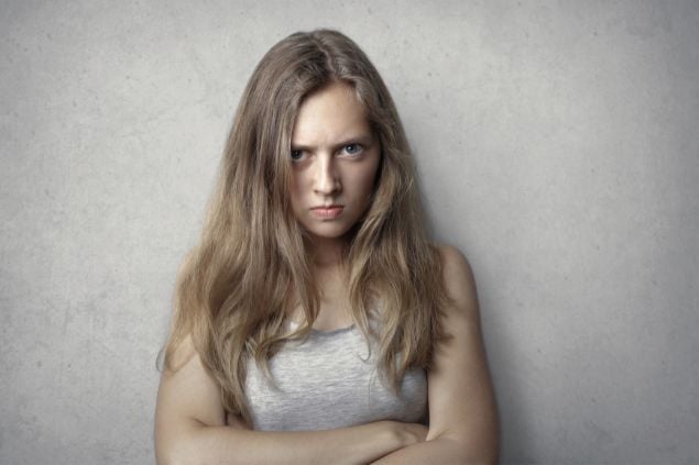 Imagem de uma mulher com os braços cruzados e expressão de raiva