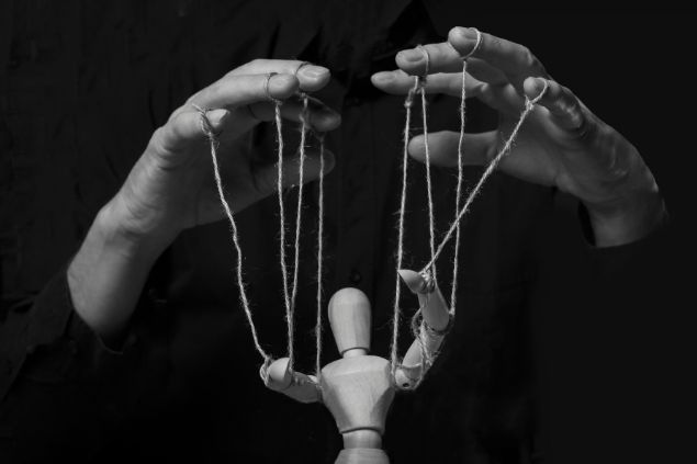 Mãos de uma pessoa manipulando uma marionete