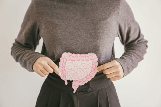 Mulher segurando um recorte de papel ilustrado e em formato de intestino