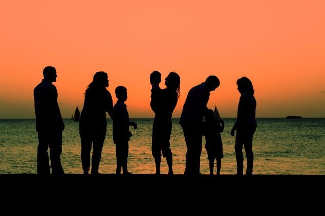 Sombra de pessoas ao pôr-do-sol em uma praia