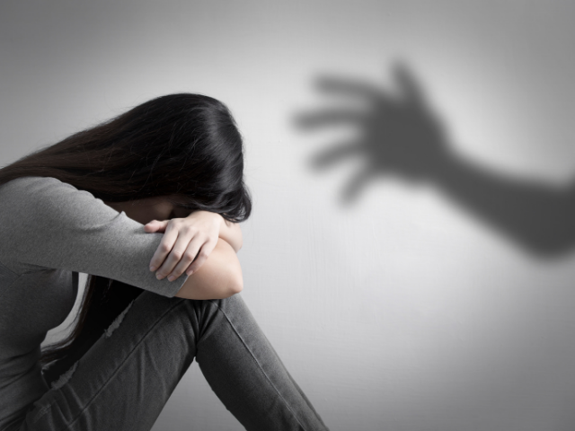 Menina de cabeça baixa e sombra de mão projetada na parede